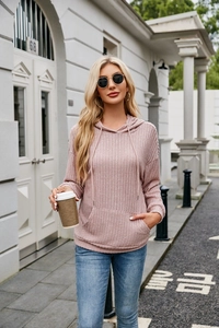 Close-up of pink ribbed knit hoodie fabric texture with kangaroo pocket and drawstring