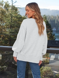 Details des hellgrauen Sweatshirts mit Rippbündchen und lockerer Passform vor Naturkulisse