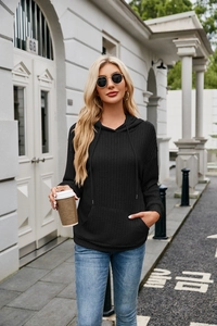 Close-up detail of black ribbed knit texture on hoodie with kangaroo pocket and drawstrings
