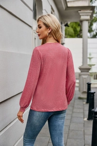 Outdoor street view showing the relaxed back silhouette of a long sleeve pink t-shirt