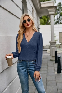 Detail of navy V-neck ribbed top with pleated collar and lantern sleeves on model