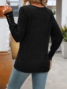 Detailed view of puff sleeves with decorative gold buttons on black long sleeve shirt