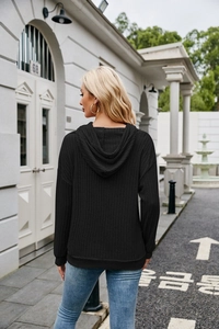 Detail view of black ribbed knit hoodie with kangaroo pocket and drop shoulder design