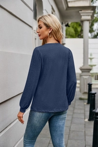 Detail showing the back view of the navy blue long-sleeve top in a casual outdoor setting