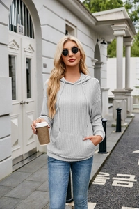 Detail of light grey ribbed hoodie featuring a kangaroo pocket and drawstring hood