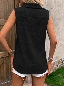 Detail view of black textured sleeveless vest featuring pleated fabric and rounded hemline
