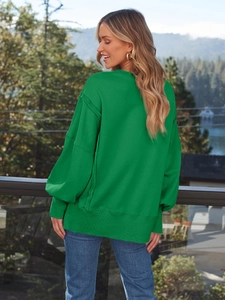Detailansicht des grünen Oversize-Sweatshirts mit Außennähten und modischen Laternenärmeln
