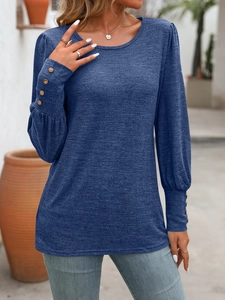 Detail of dark blue knit top featuring puff sleeves and brown decorative cuff buttons