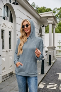 Detailed view of rib-knit fabric texture and kangaroo pocket on light blue hoodie