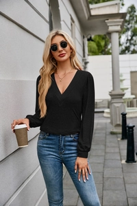 Detailed view of women's black V-neck long sleeve top with textured knit fabric