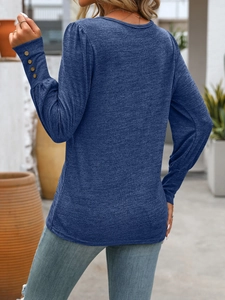 Detail showing the sleeve cuffs with four decorative brown buttons on the blue knit shirt
