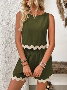 Detail of dark green linen set showing white wavy lace trim on the hem and shorts