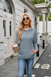 Detail of blue knitted hoodie featuring ribbed texture and classic front kangaroo pocket