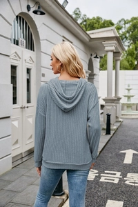 Rear view of blue-gray ribbed knit hoodie showing relaxed fit and hooded structure