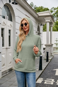 Detailed texture of sage green ribbed knit hoodie featuring drawstring hood and pocket