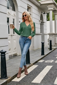 Detail of dark green V-neck long sleeve knit top with slim blue jeans and ankle boots