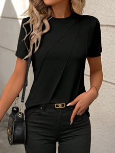 Detail of black crew neck T-shirt featuring asymmetric pleated drape and stylish gold chain belt
