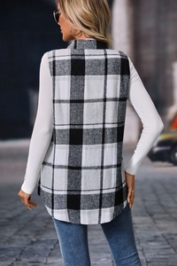 Vista posteriore di un lungo gilet a quadri bianco e nero sopra un maglione di maglia bianco
