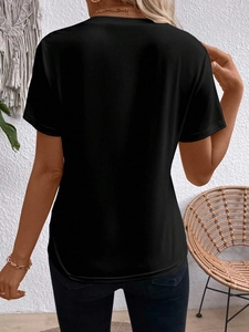 Back view of a black round neck short sleeve T-shirt on a model in a cozy home setting