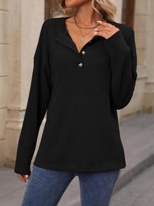 Dettaglio della maglia a coste sul top Henley nero con bottoni funzionali sullo scollo a V