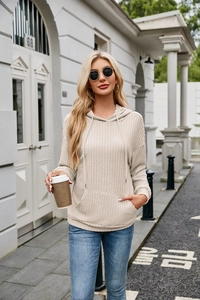 Detail of knitted ribbed hoodie fabric with drawstring and kangaroo pocket in beige color