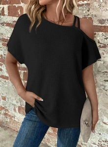 Detail of black waffle knit off-shoulder top with strap and textured fabric finish