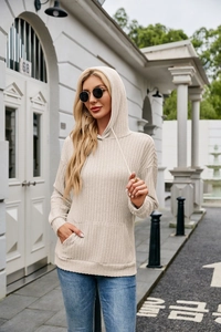 Detail of beige ribbed knit hoodie featuring drawstring hood and kangaroo pocket