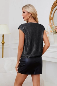 Détail d'un haut à paillettes noires scintillantes avec une jupe élégante en similicuir