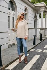 Close-up of beige ribbed knit texture on a women's drawstring hoodie with kangaroo pocket