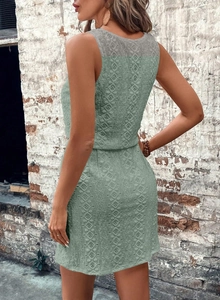 Detailed close-up of sage green lace mini dress with intricate hollow-out floral patterns