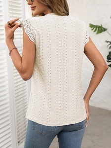 Detail view of cream crochet sleeveless top showing geometric lace patterns and scalloped trim