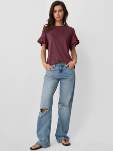 Detail of wine red round neck top with tiered ruffle sleeves and distressed denim jeans