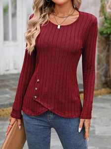 Detail of dark red ribbed knit top featuring side buttons and asymmetric crossover hem
