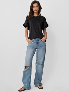 Detail of black T-shirt with layered ruffle sleeves paired with ripped wide-leg jeans