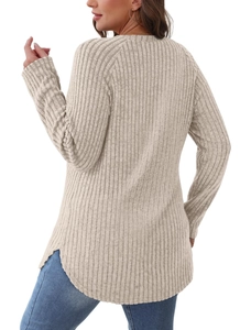 Dettaglio della maglia beige a costine con orlo curvo asimmetrico e spacchi laterali