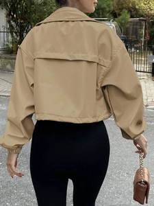 Detail view of khaki short jacket showing the storm flap and elastic cuffs on the back