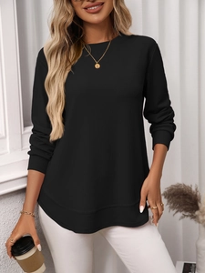 Detail view of black waffle knit long sleeve top featuring ribbed cuffs and a curved hemline