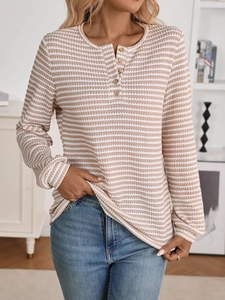 Detailed close-up of textured waffle knit fabric and wooden buttons on the Henley collar