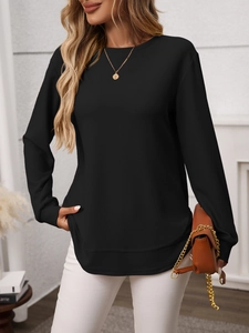 Detail of waffle knit fabric and curved hem design on a casual long sleeve black top