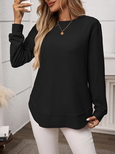 Detailed macro view of black waffle knit fabric and curved hem on women's long sleeve top