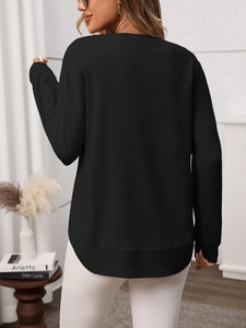 Detail view showing the back of a black waffle knit top with a curved hem and ribbed cuffs