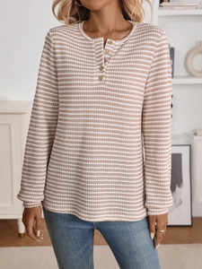 Detail of waffle knit fabric texture and decorative wooden buttons on striped long sleeve top