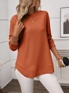 Detail of waffle knit fabric and layered curved hem on a terracotta long sleeve top