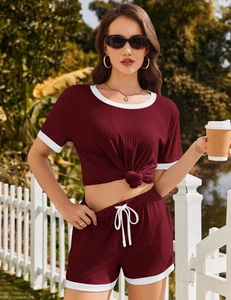 Detail von burgunderrotem Ripp-Pyjama-Set mit weißem Kontrastrand und modischem Knotendesign