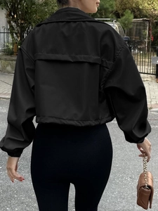 Back view of a cropped black windbreaker jacket showing loose sleeves and fabric texture