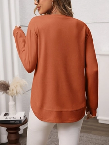 Detail of waffle knit fabric texture and curved hem on burnt orange long sleeve top