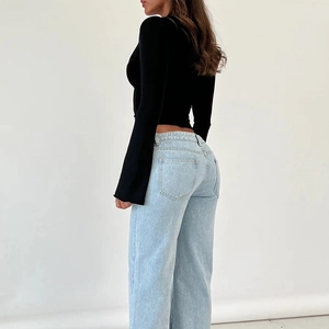 Detail of black V-neck lace top with button design and light blue wide-leg denim jeans