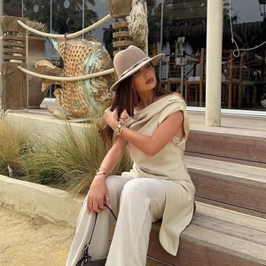 Dettaglio del top asimmetrico beige e dei pantaloni larghi in lino per lo stile resort