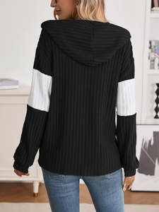 Back view of a color-block ribbed knit hoodie featuring black and white contrast sleeves