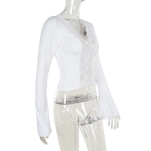 Close-up of white long sleeve top with delicate floral lace trim on V-neck and front
